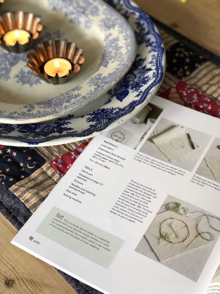 open book on table cloth with tealights and plates