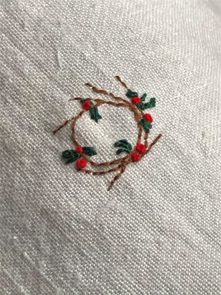 Stitching a Christmas wreath onto linen