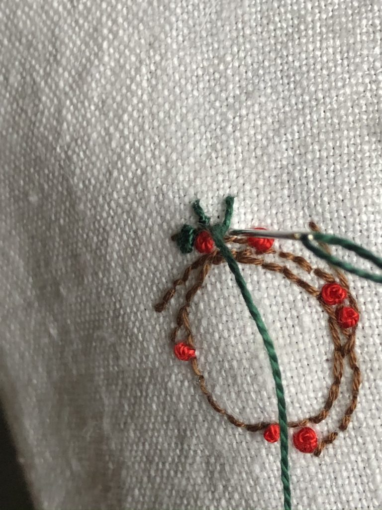 Stitching a Christmas wreath onto linen