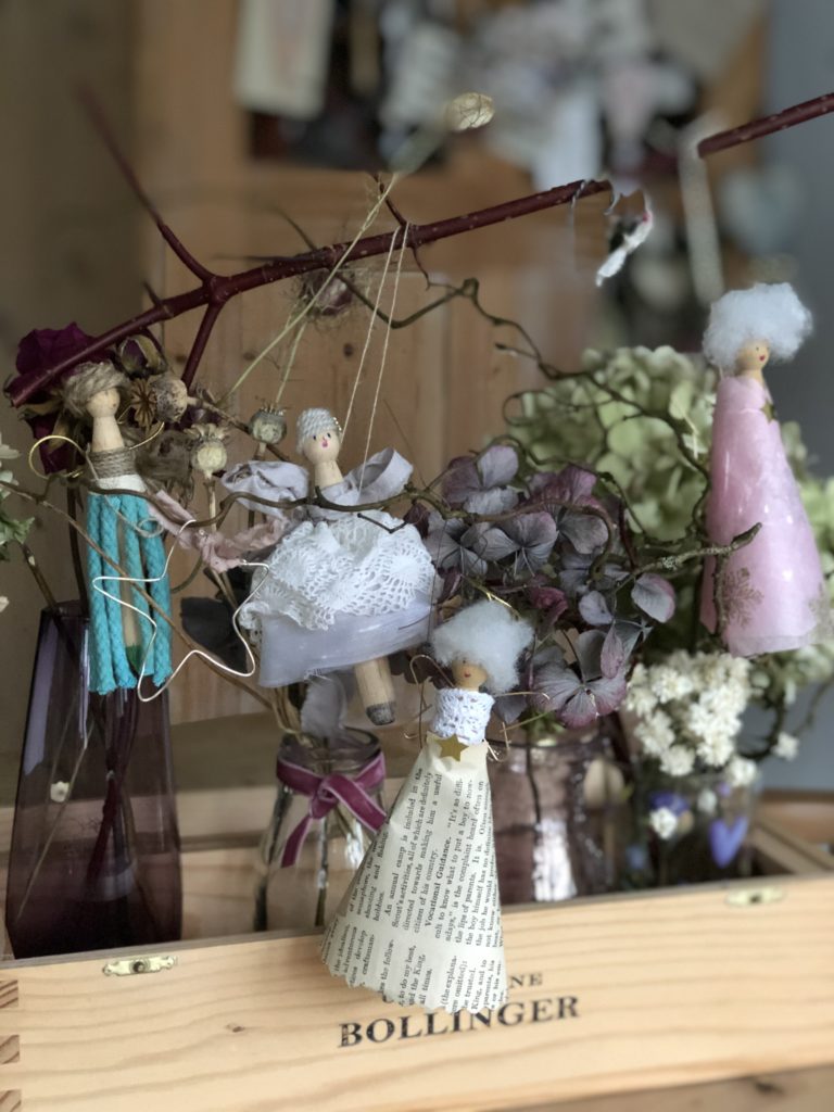 four peg doll Christmas fairies hanging amongst dried hydrangeas