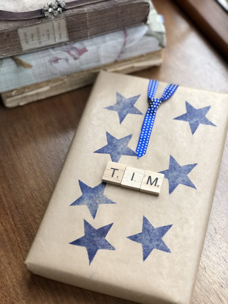 blue ink stars on brown wrapping paper with wooden letter tiles and ribbon