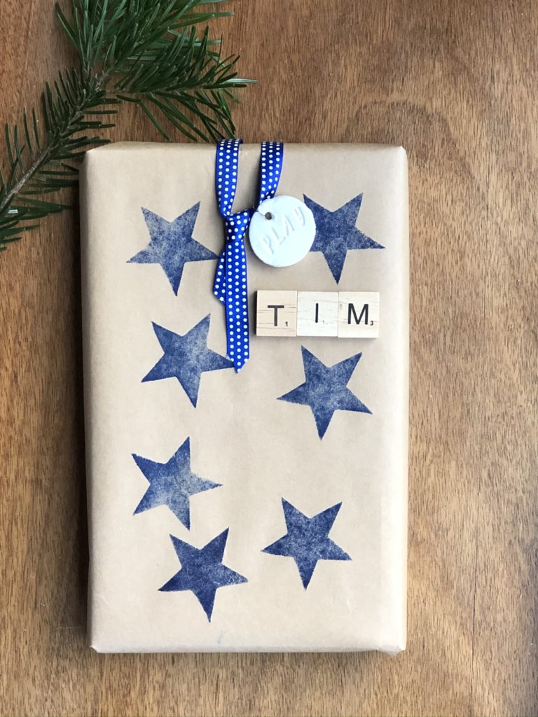 blue ink stars on brown wrapping paper with wooden letter tiles and ribbon