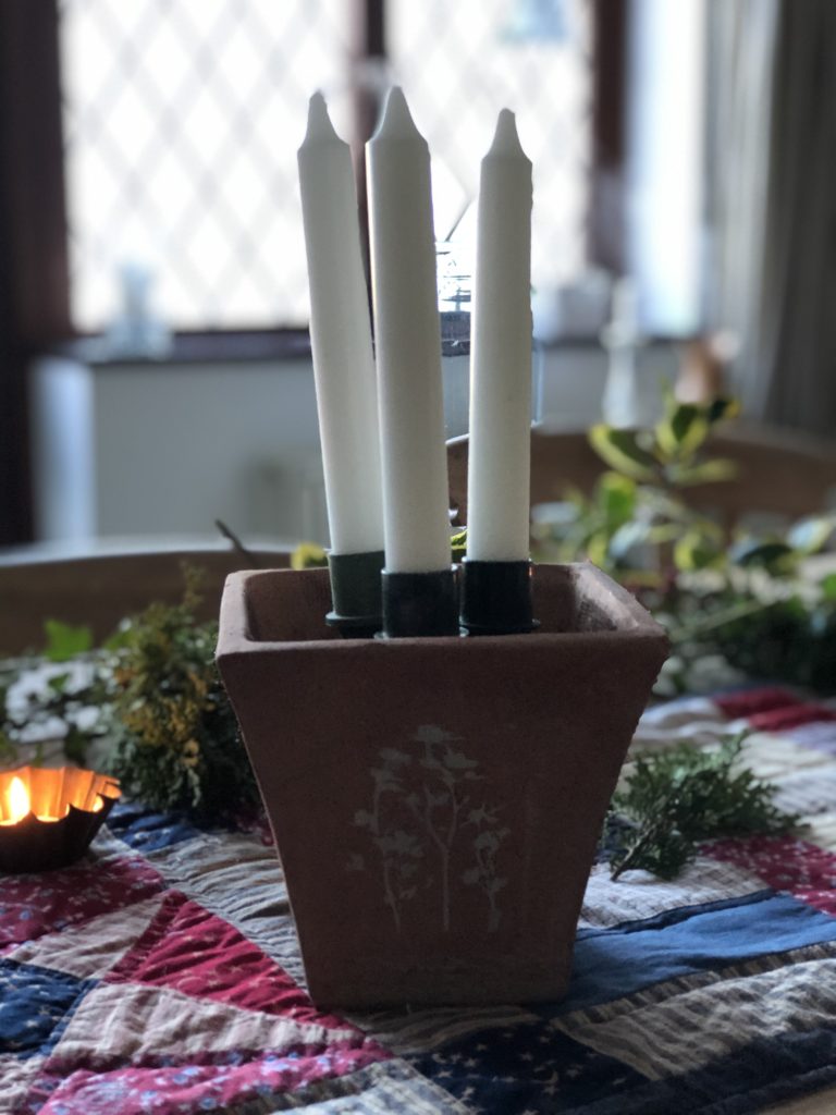 three white candles in terracotta stenciled pot