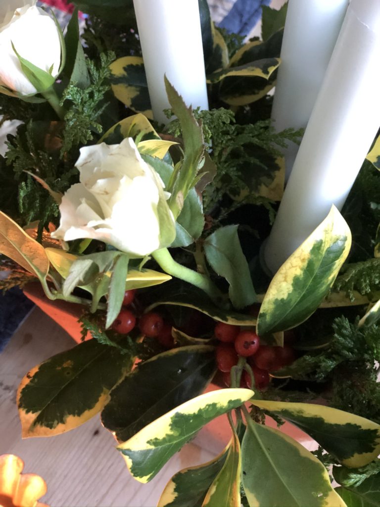 foliage, candles and berries and roses in terracotta pot