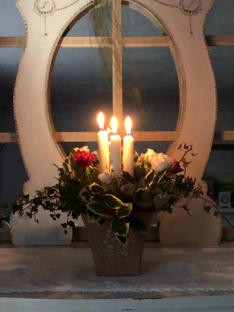 lit candle and flower arrangement on sideboard with mirror backdrop