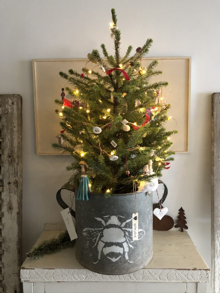 homemade rustic decorations on mini christmas tree in zinc bucket