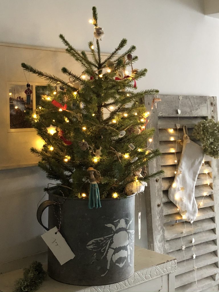 homemade rustic decorations on mini christmas tree in zinc bucket