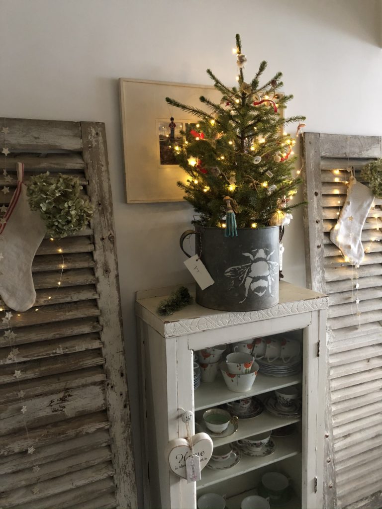 homemade rustic decorations on mini christmas tree in zinc bucket and rustic shutters