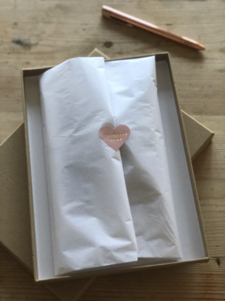 white tissue wrapped gift with pink heart sticker