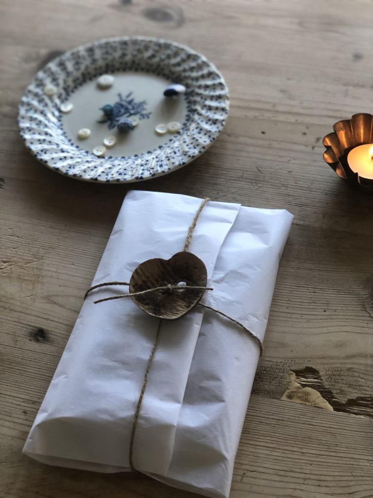 white tissue paper wrapped gift with string and wooden heart bow