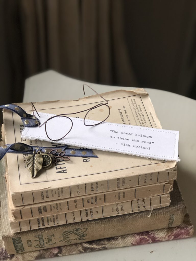 stack of vintage books with wire glasses and handmade bookmarks