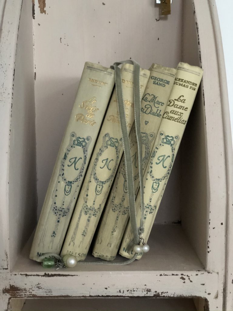 french book spines on pink wooden shelf