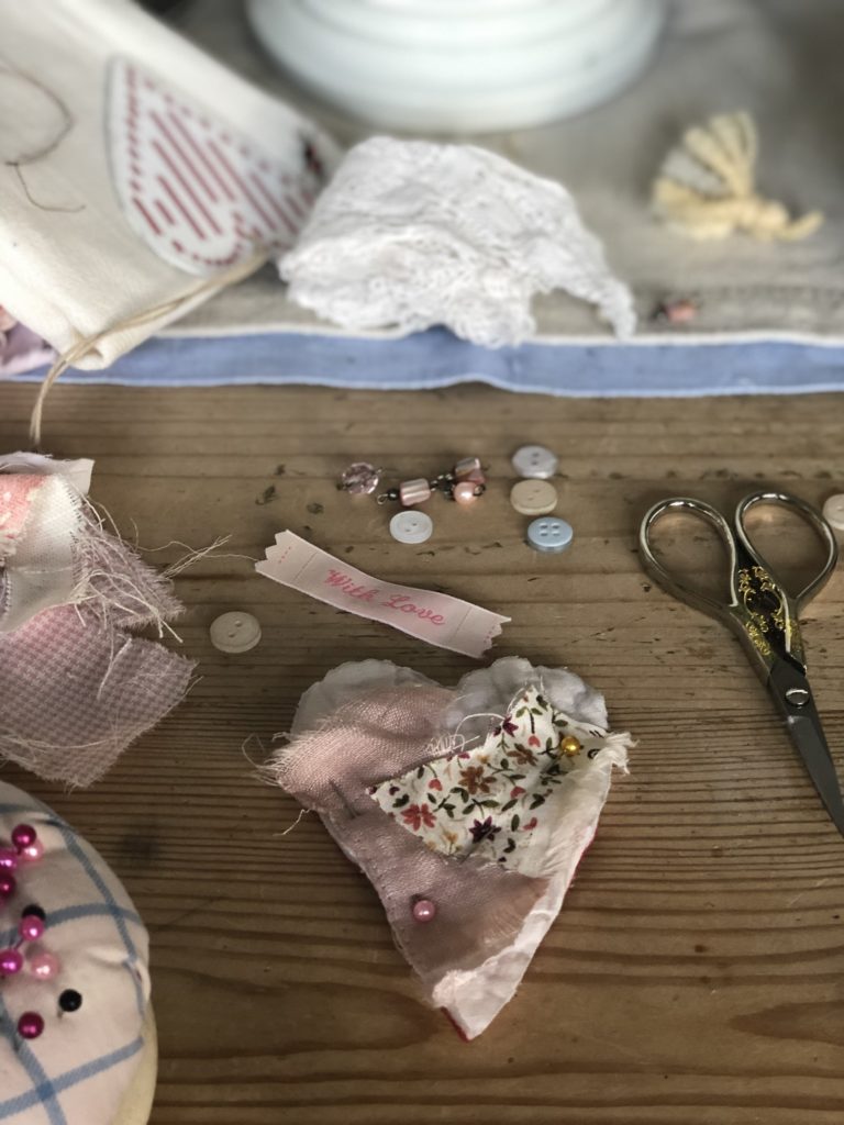 making a fabric heart brooch with material scraps, labels and buttons