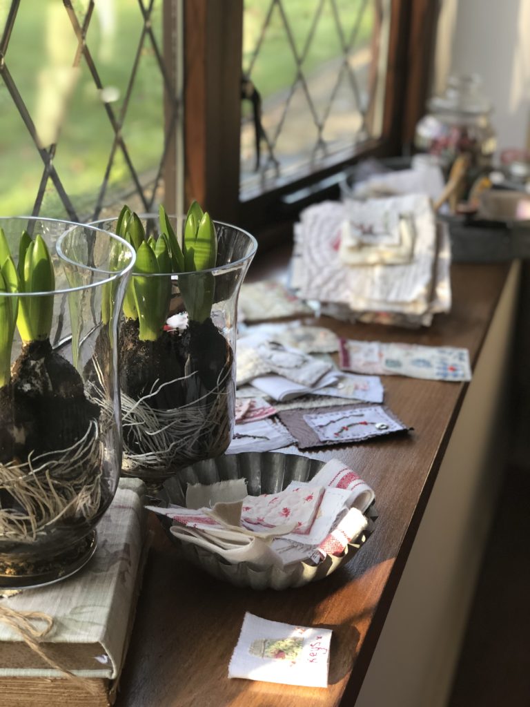 vintage fabrics and spring bulbs on window sill in sunlight