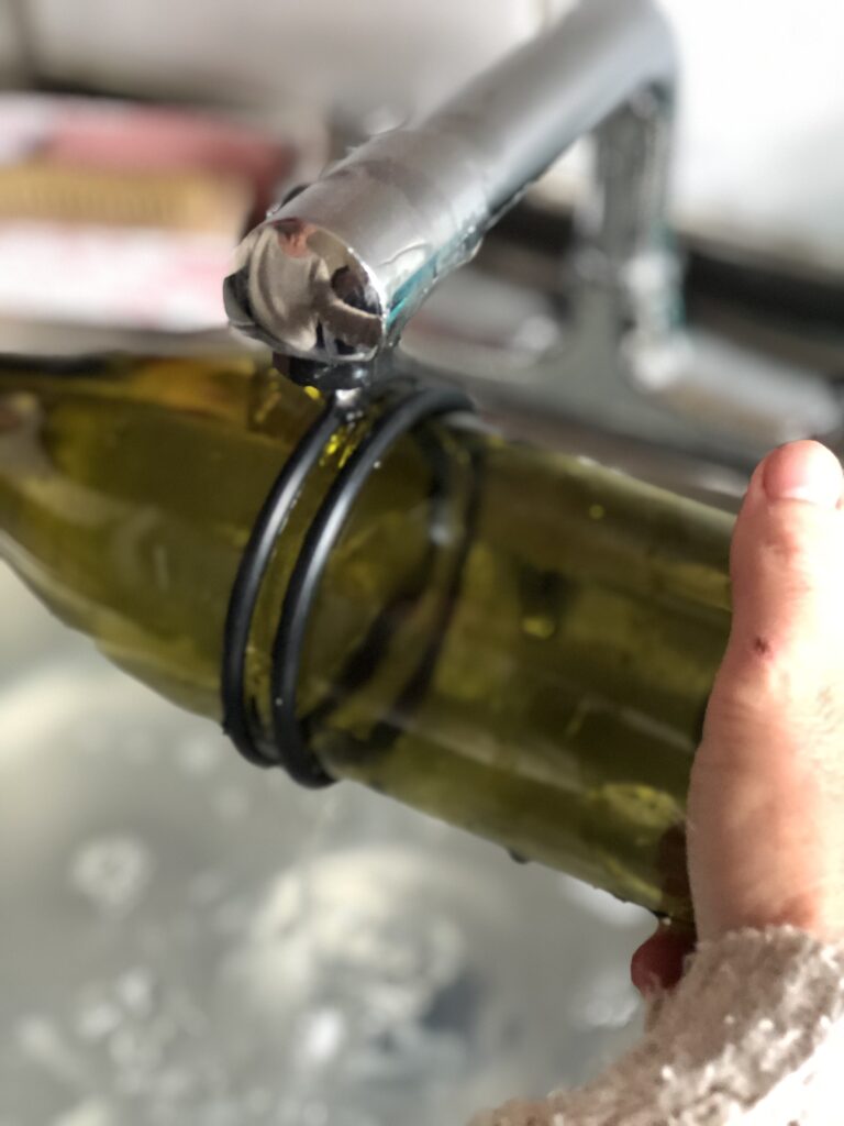 running scored wine bottle under running water