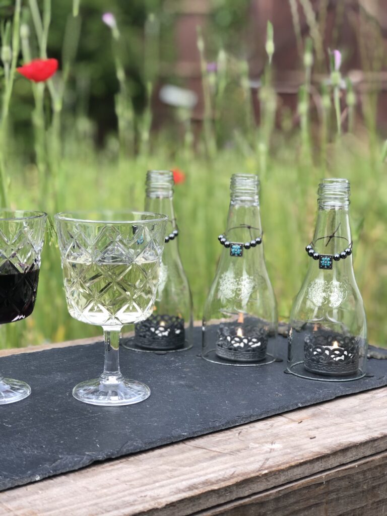 glasses of wine on glass bottle decoration on wooden crate in wildflower meadow