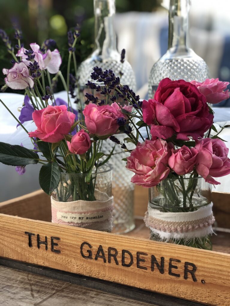 recycled wine bottle lamps and glass vases with pretty flowers in garden tray