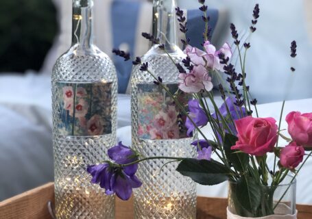 recycled wine bottle project with fairy lights and garden flowers