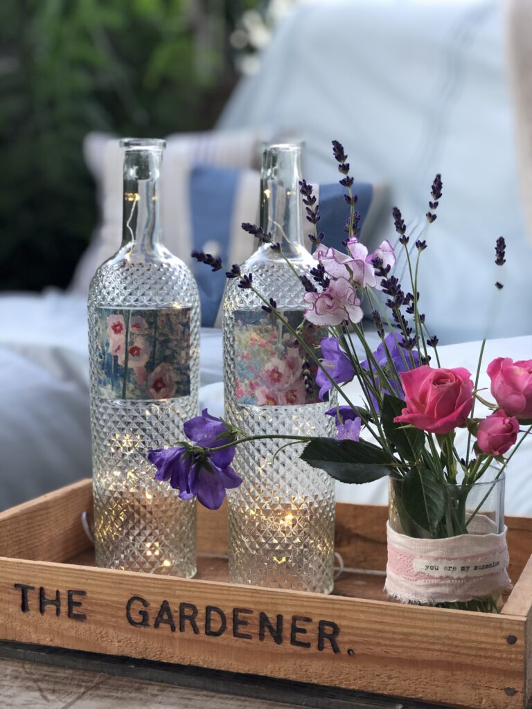 recycled wine bottle project with fairy lights and garden flowers