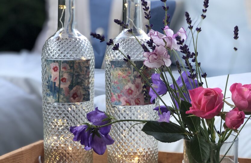 recycled wine bottle project with fairy lights and garden flowers