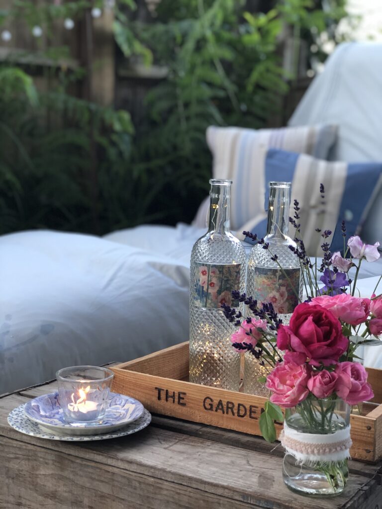 recycled wine bottles with candle and flowers in pretty garden setting