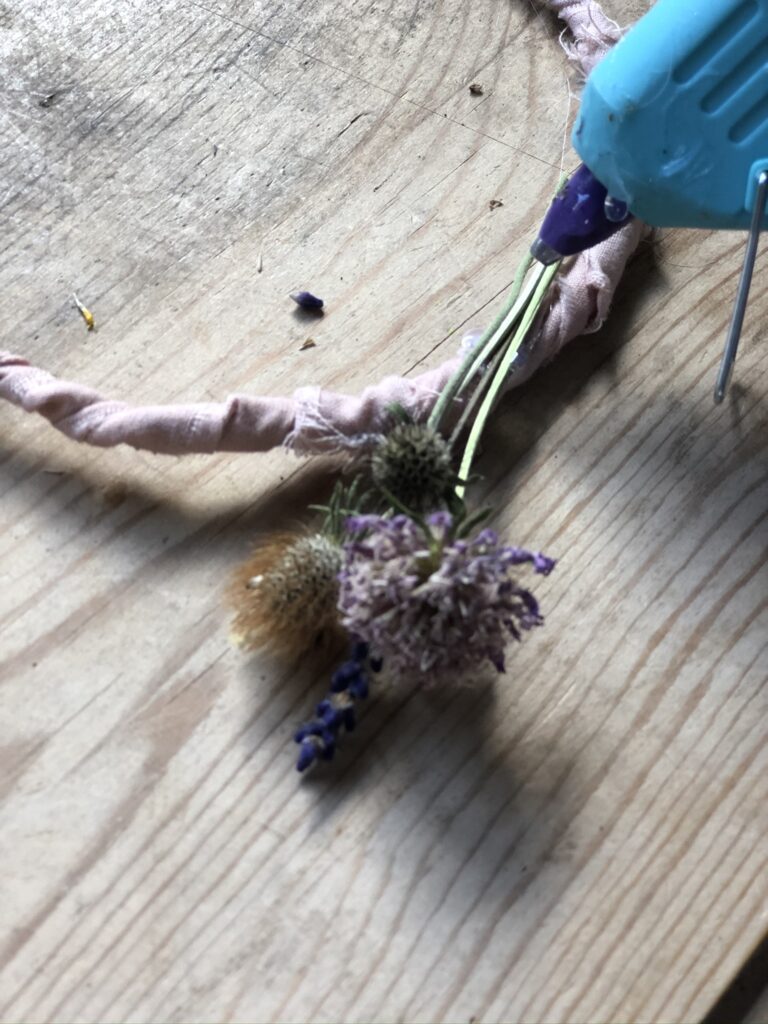 hot glueing dried flowers to rag ribbon