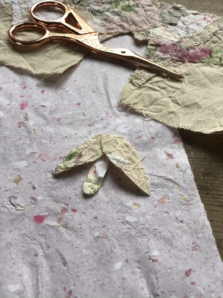 scrap fabric petals and scissors on homemade paper