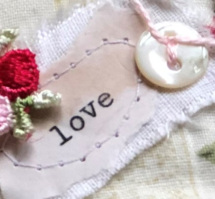 stitching typewritten word love to fabric with trim and button