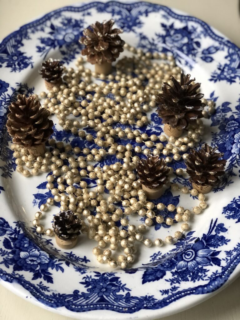 beads and pine cones on blue and white platter