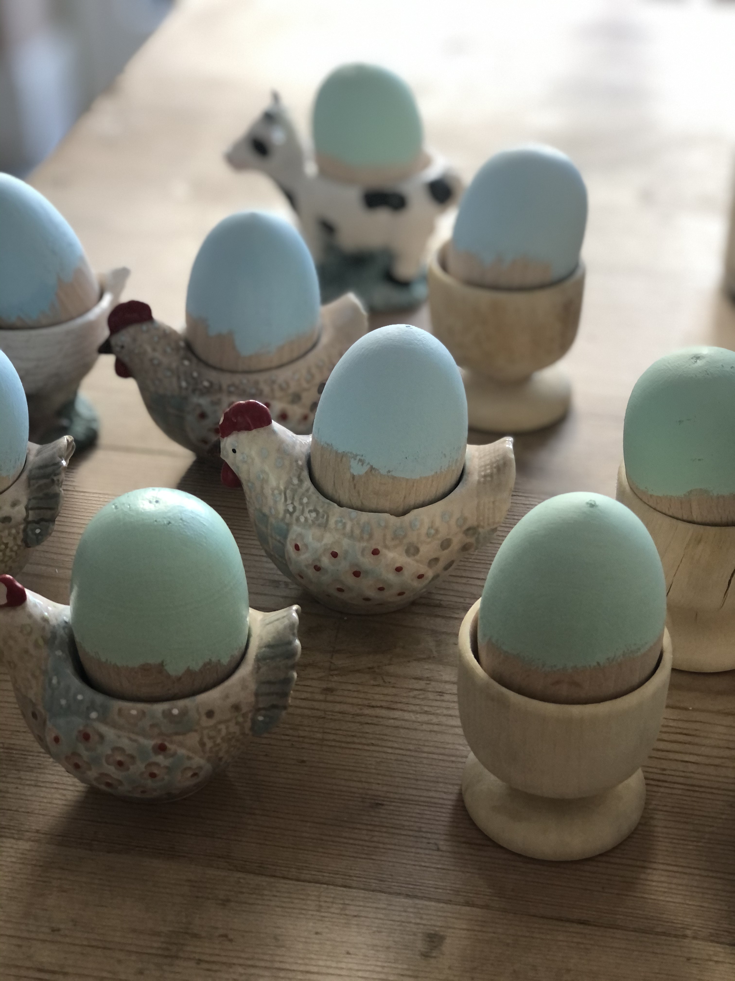 half painted wooden easter eggs in variety of egg cups for simple easter table centrepiece