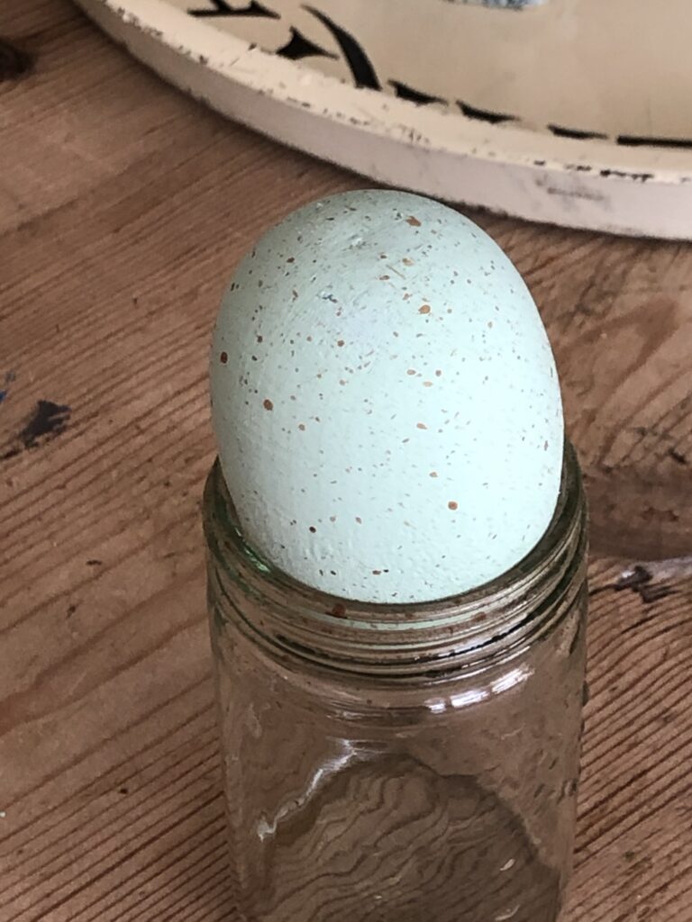 green painted egg speckled with brown paint