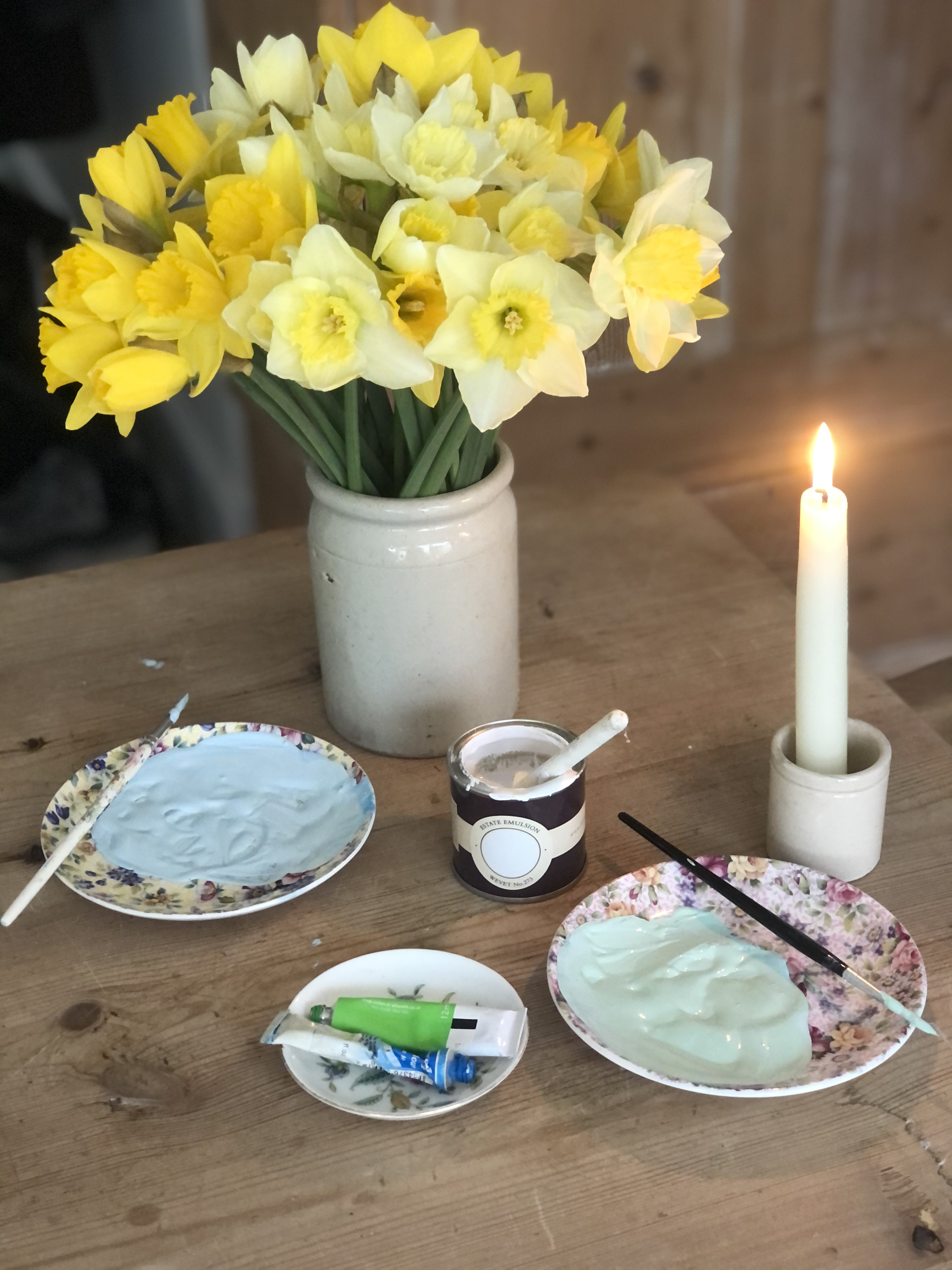 daffodils and paints in teaplates with candle