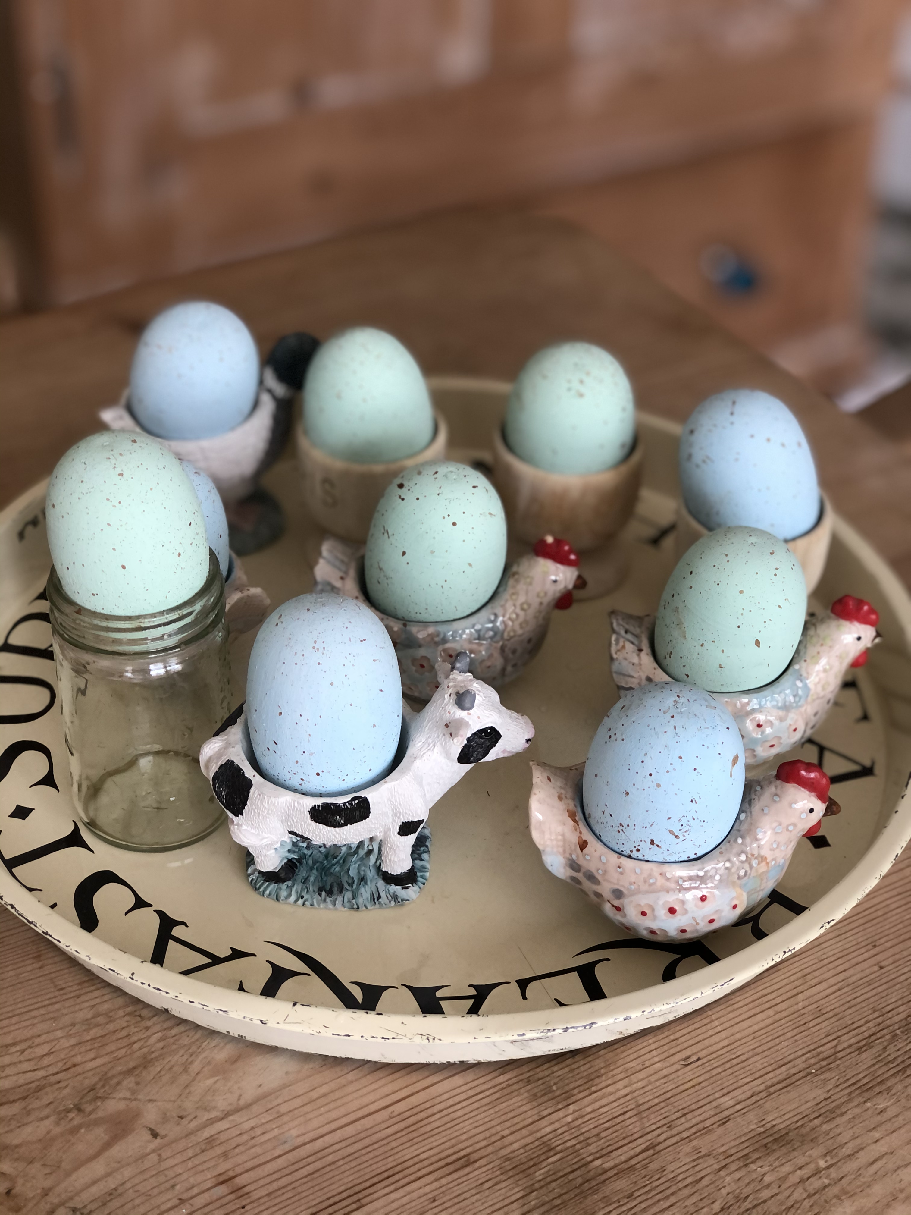 painted wooden eggs in variety of egg cups on Emma Bridgewater tray for homemade easter table centrepiece