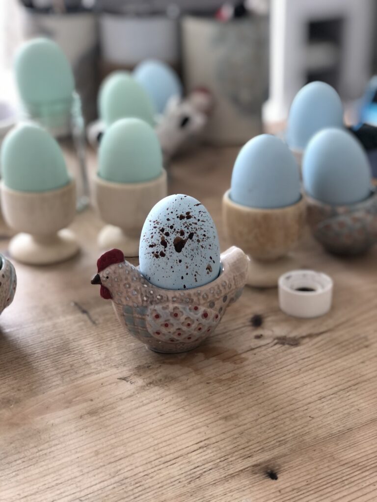 blue painted egg speckled with brown paint