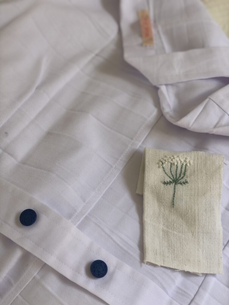 blue buttons and cow parsley embroidery to a white lab coat in sunshine