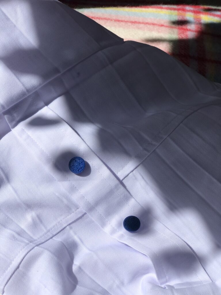 two blue buttons on white lab coat in sunshine