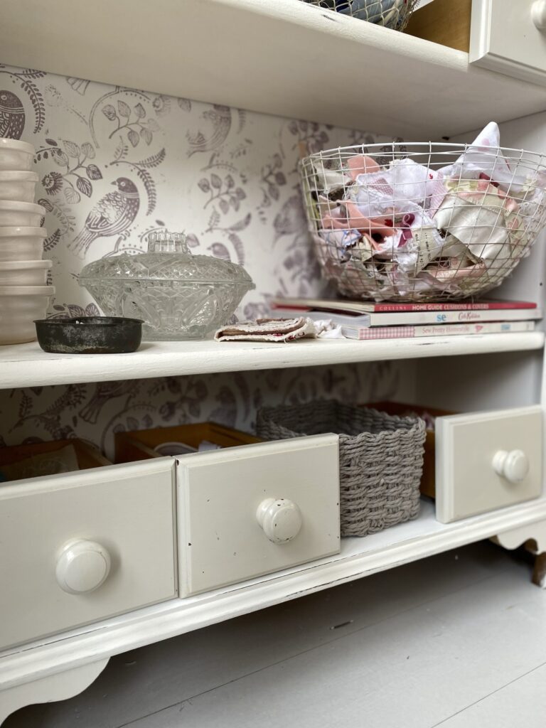 shelves full of drawers and baskets and fabrics in craft room