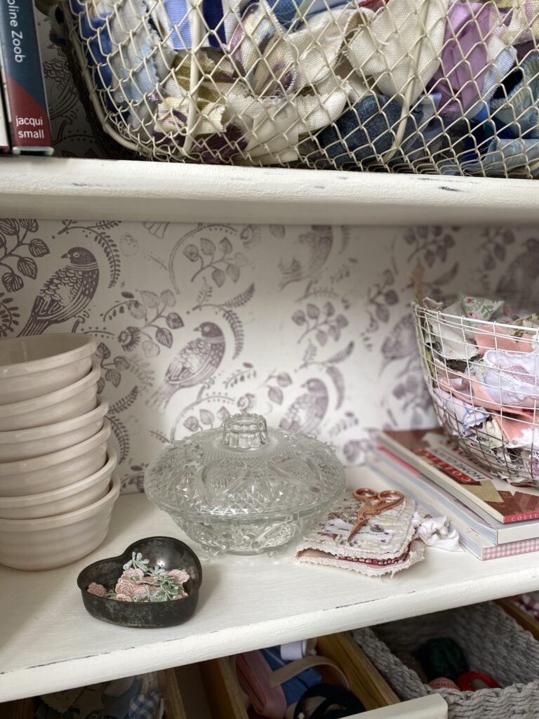 shelves on an upcycled bookcase full of crafty bits