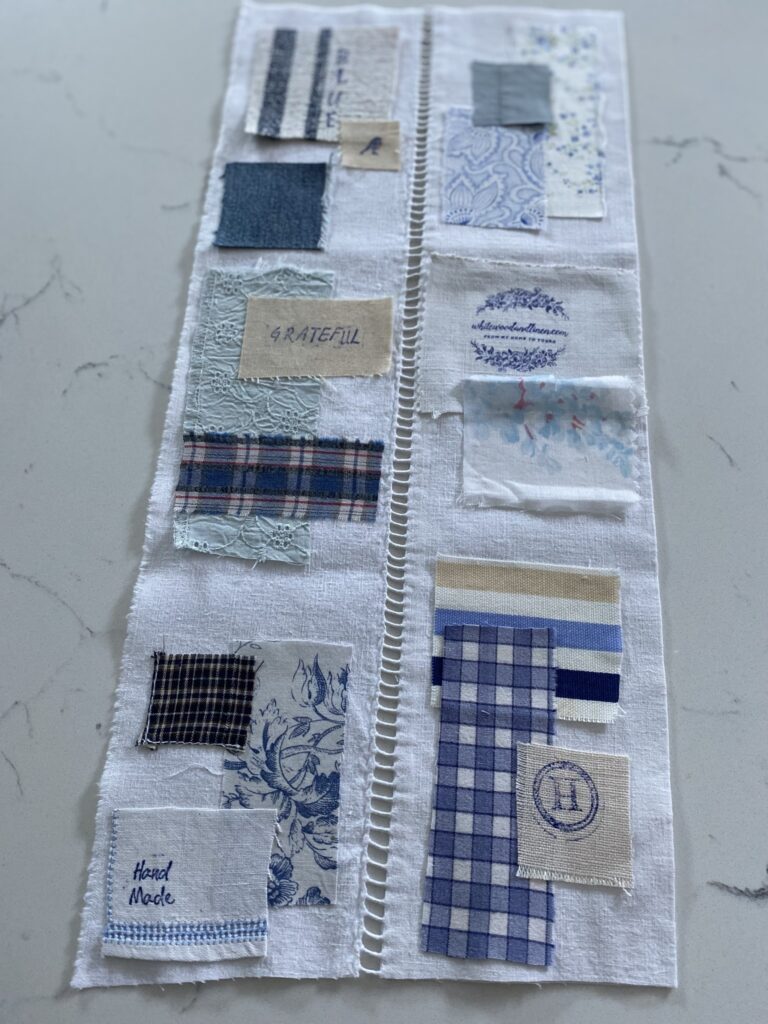 arranging blue and white fabric scraps on white linen for sampler