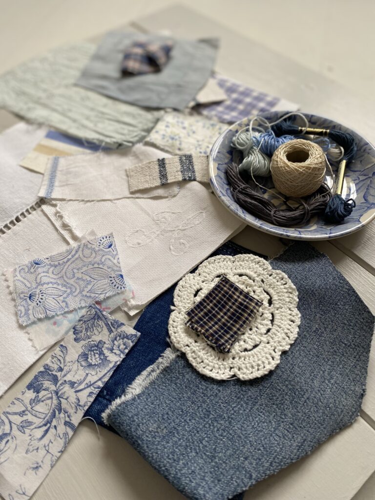 variety of blue and white fabric scraps and threads on a blue plate