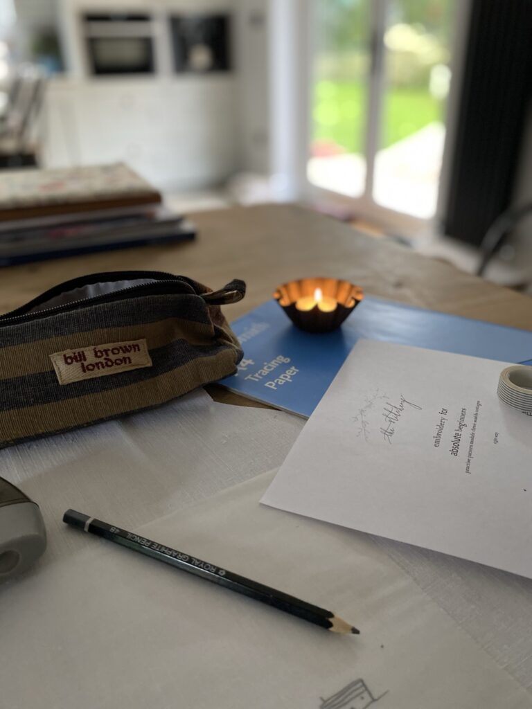 pencil case, candle, tracing paper and pattern and pencil on table top