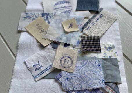 arranging blue and white fabric scraps on white linen for sampler