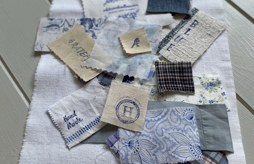 arranging blue and white fabric scraps on white linen for sampler