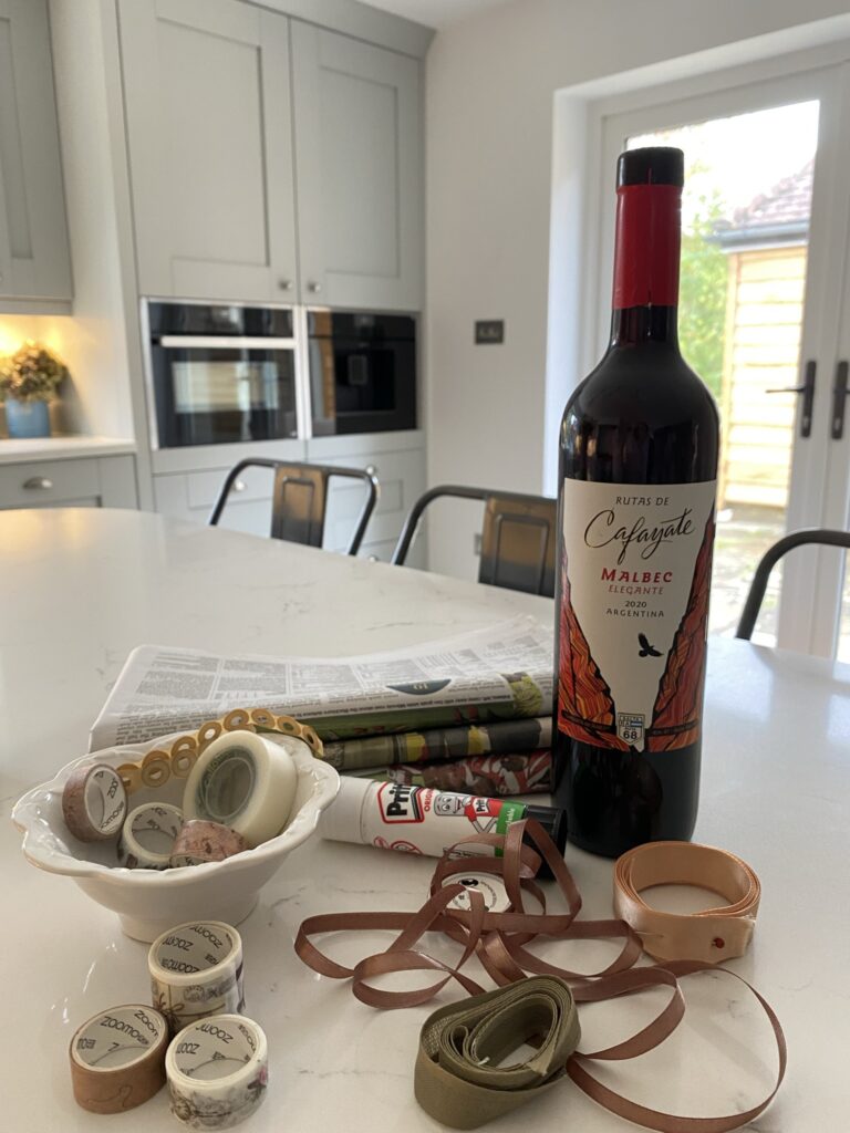 red wine, washi tape, ribbons, glue stick and newspaper on kitchen surface