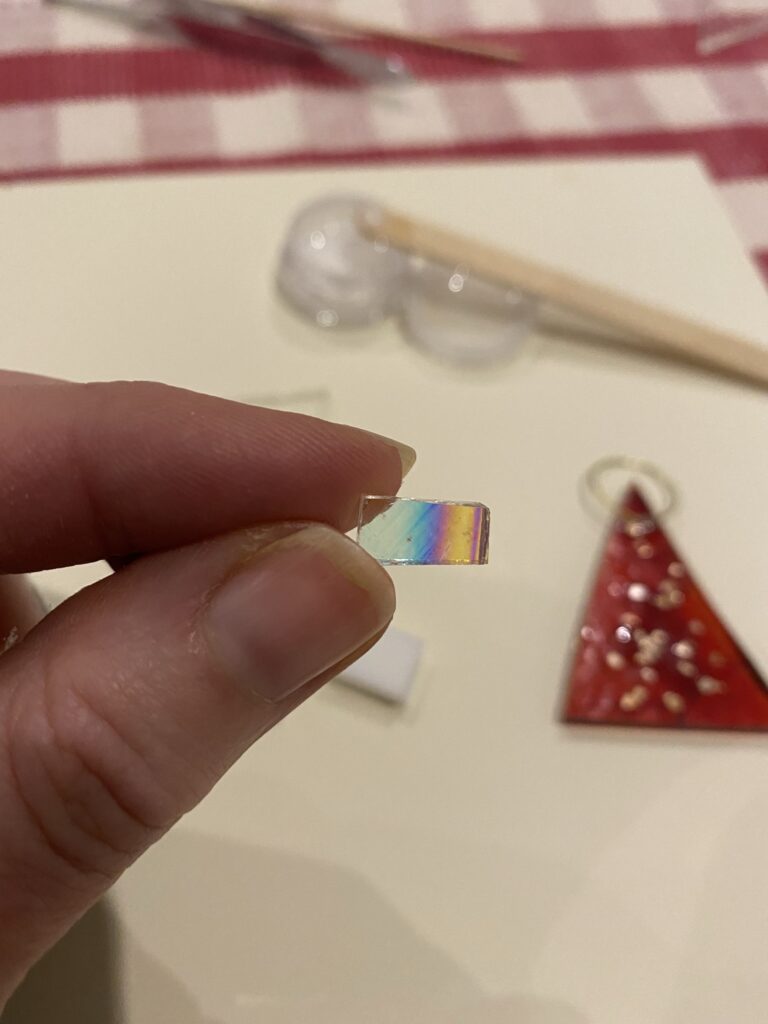 fingers holding iridescent glass from glass crafting kit