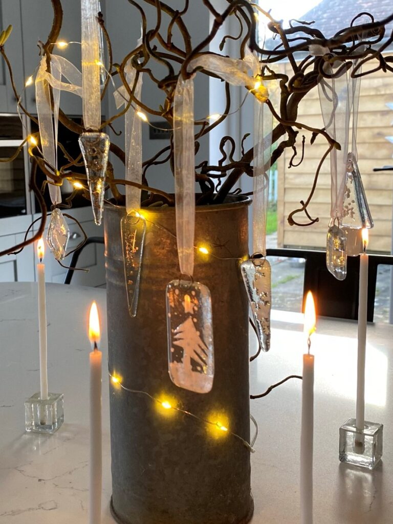 hanging glass decorations on twig tree with fairy lights and tapered candles