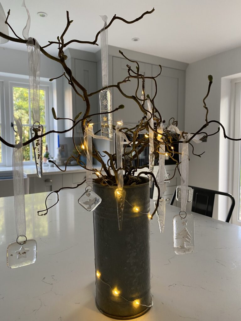 a twig tree with with fairy lights and handmade glass seasonal decorations