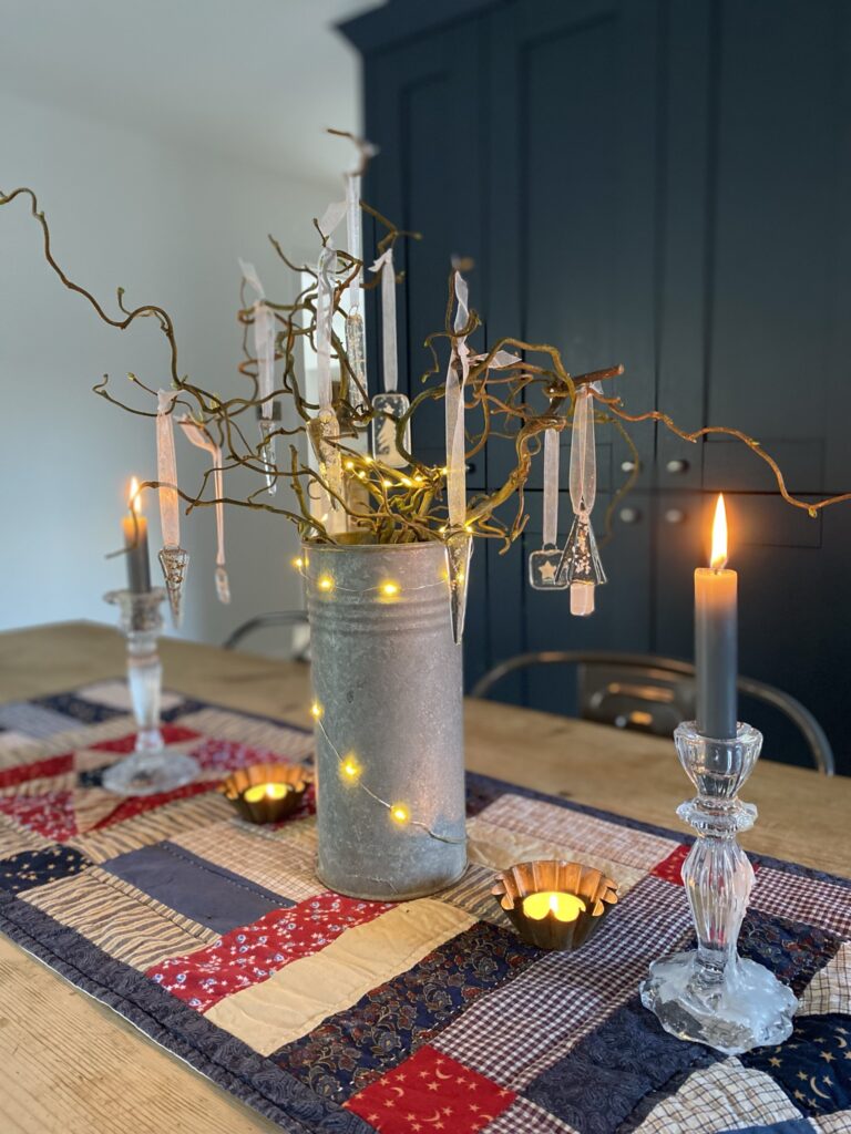 twig tree with fairy lights, candles and beautiful clear glass decorations on shaker style table runner 