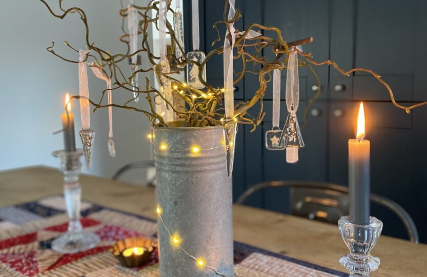 twig tree with fairy lights, candles and beautiful clear glass decorations on shaker style table runner