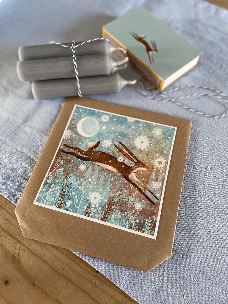 making a diy gift bag with christmas card, paper and string and candles